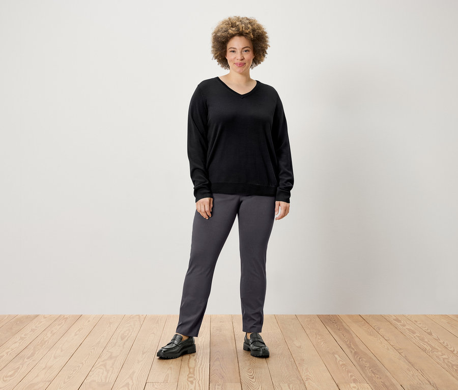 Frau posiert in Pullover und Stretchhose.