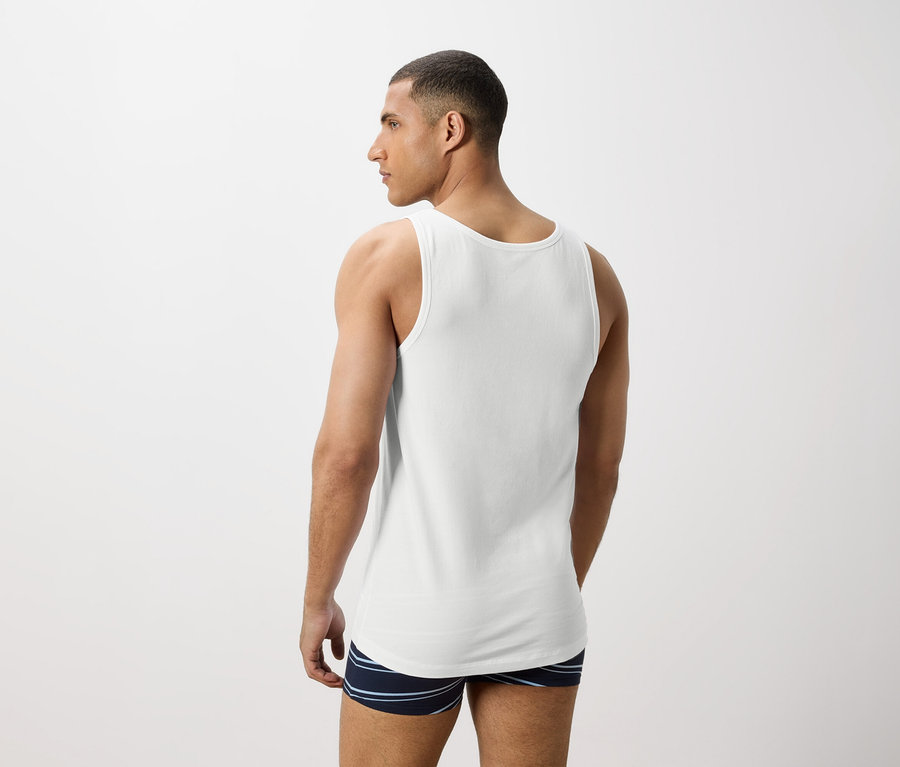 Mann von hinten in weißem Tanktop und gestreiften Boxershorts.