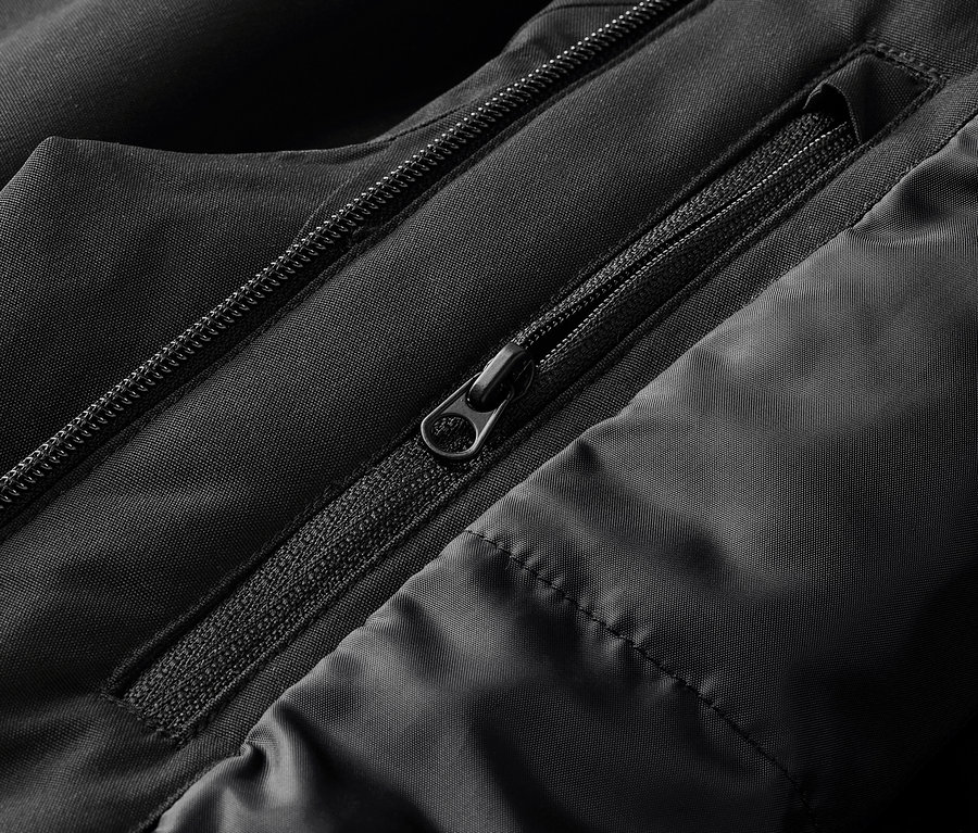 Detailaufnahme einer schwarzen Jacke mit sichtbaren Reißverschlüssen und Steppnähten.