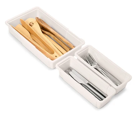 Sets von weißen Schubladen-Organisatoren mit Küchenutensilien aus Holz und Silber.