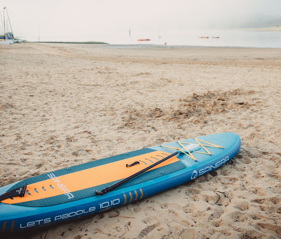 Blaues Spinera SUP Board Lets Paddle 10'10" liegt am Sandstrand.