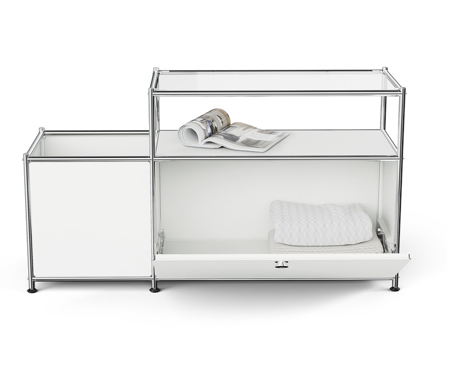 Weißes modulares Aufbewahrungssystem mit offenen Regalen und einer Schublade, mit einer Zeitschrift im obersten Regal und gefalteten Textilien in der Schublade.