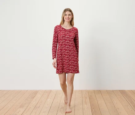 Eine Frau geht barfuß über einen Holzboden und trägt ein rotes, langärmliges Kleid.