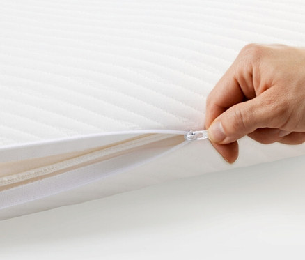 Hand öffnet weißen TEMPUR PRIMA® Schlafkissen Medium mit Reißverschluss.