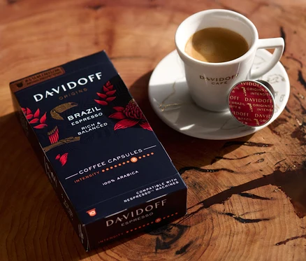 Auf einem Holztisch stehen eine Packung DAVIDOFF CAFÉ ORIGINS Brazil Espresso, eine Tasse Espresso und eine Kapsel.