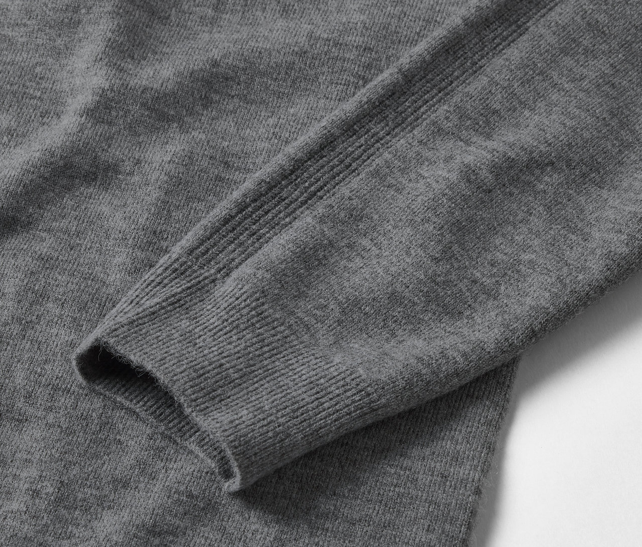 Detailaufnahme eines grauen Langarmpullovers.