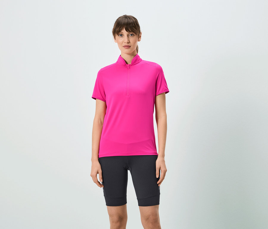 Frau trägt ein pinkes T-Shirt mit kurzem Reißverschluss und schwarze Shorts.