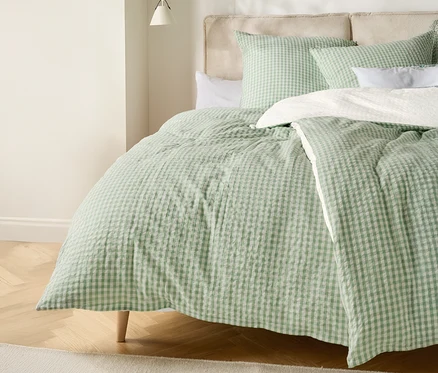 Ein Bett mit einer hellgrün-weiß karierten Bettdecke und passenden Kissen.
