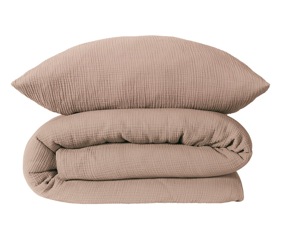 Ein beigefarbenes Kissen liegt auf einer zusammengerollten beigefarbenen Decke.