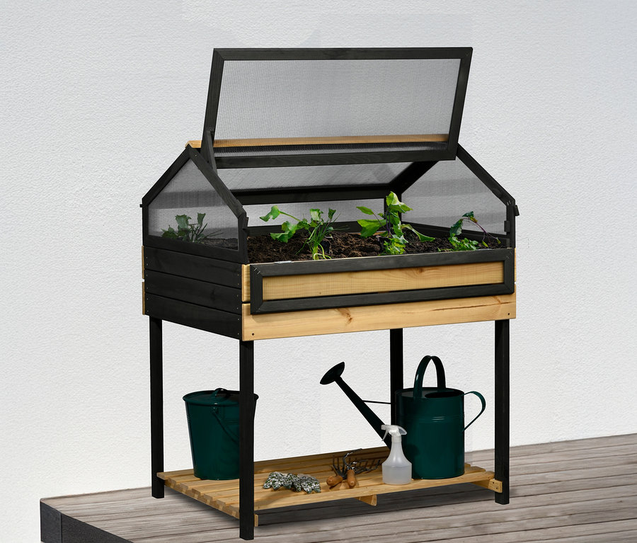 Ein 4-Jahreszeiten-Hochbeet, XXL mit geöffnetem Netzdeckel steht auf einer Holzterrasse. Unter dem Beet befinden sich eine Gießkanne, ein Eimer und Gartengeräte.
