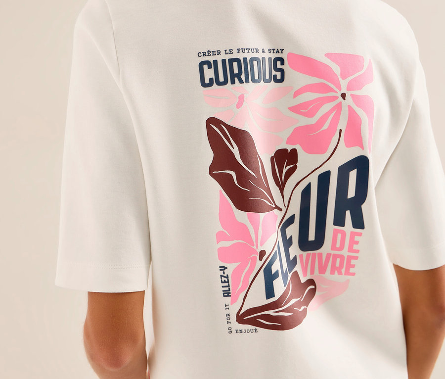 Eine Person von hinten trägt ein weißes CECIL Sweatshirt mit einem bunten Grafikdruck auf dem Rücken. Der Druck zeigt rosa Blumen, braune Blätter und Text wie „CRÉER LE FUTUR & STAY CURIOUS“ und „FLEUR DE VIVRE“.
