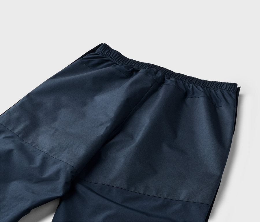 Nahaufnahme der Rückseite einer marineblauen Hose mit elastischem Bund auf einem weißen Hintergrund.