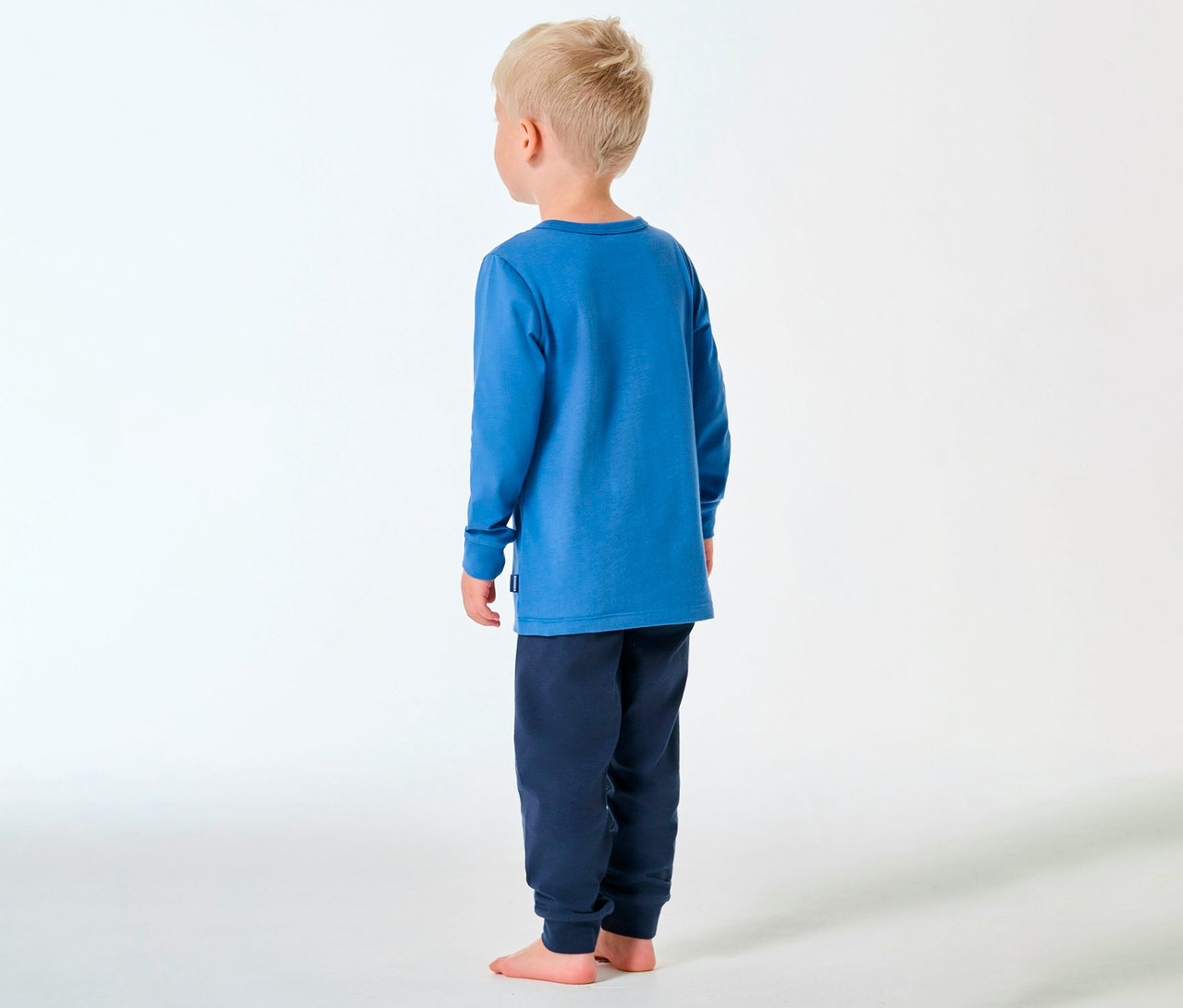 Junge von hinten, barfuß, trägt blauen SCHIESSER Kinder-Pyjama.
