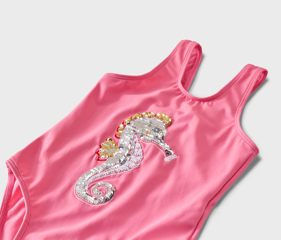 Nahaufnahme eines pinkfarbenen Badeanzugs mit einem silbernen und goldenen Seepferdchen-Paillettenmuster.