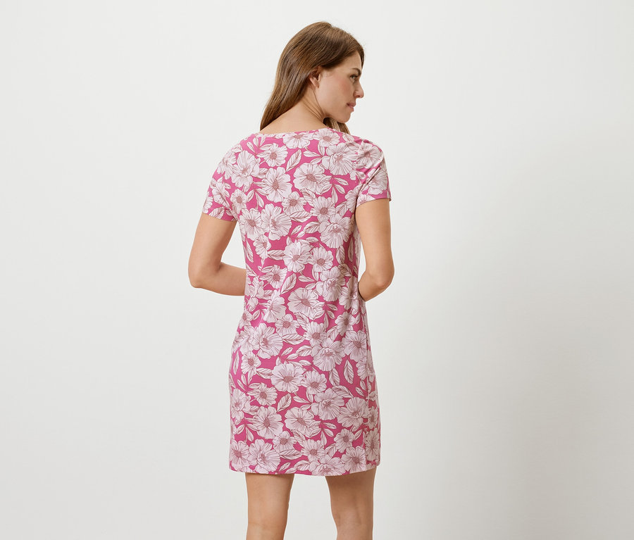 Eine Frau steht mit dem Rücken zur Kamera und trägt ein pinkfarbenes Kleid mit Blumendruck.