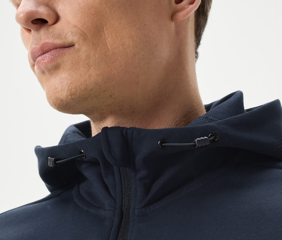 Nahaufnahme eines Mannes, der einen marineblauen Kapuzenpullover mit Reißverschluss trägt.
