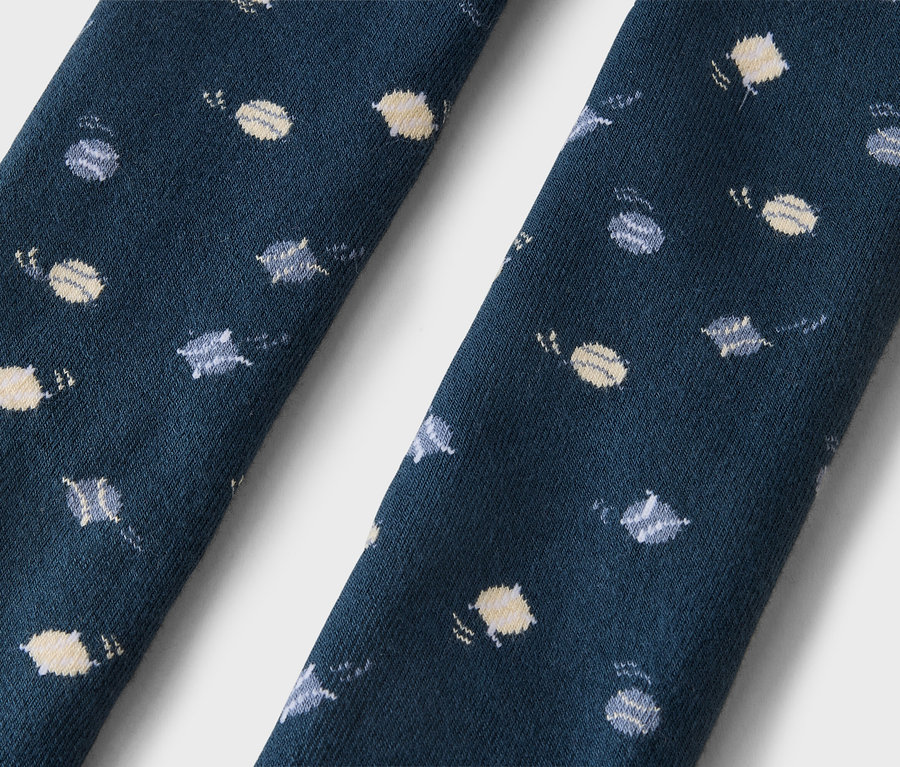 Nahaufnahme von zwei dunkelblauen Stoffabschnitten, möglicherweise Socken, mit einem sich wiederholenden Muster aus kleinen hellgelben und grauen Planeten und Sternen.