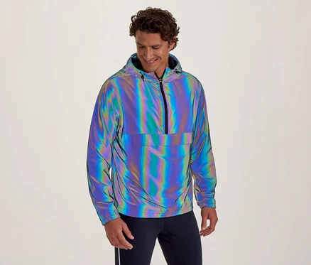 Lächelnder Mann in reflektierender, irisierender Kapuzenjacke mit halbem Reißverschluss und Bauchtasche, blickt nach unten.