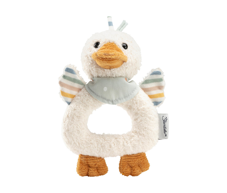 Ein Plüsch-Babyrassel in Form einer weißen Ente mit ringförmigem Körper. Sie hat einen orangefarbenen Schnabel, orangefarbene Schwimmhäute an den Füßen, kleine gestreifte Flügel in Pastellfarben und ein hellblaues Lätzchen mit weißen Punkten um den Hals.