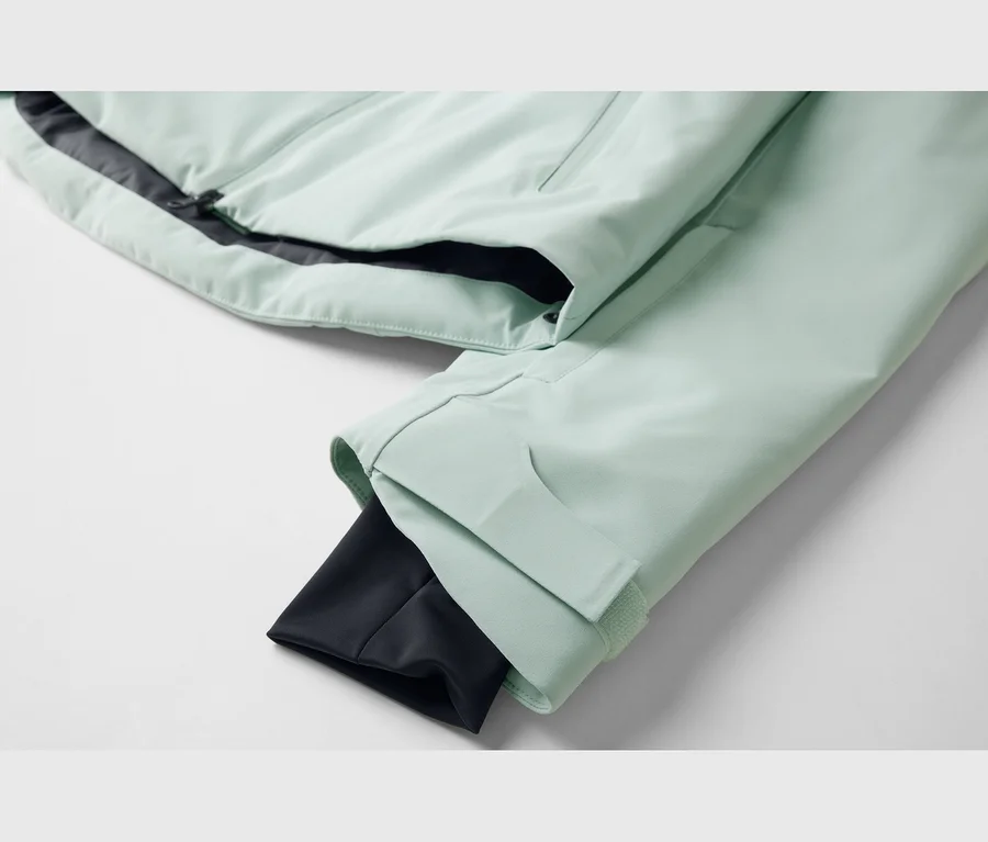 Hellgrüne Jacke mit schwarzem Reißverschluss und schwarzem Innenfutter. Der Ärmel hat eine verstellbare Manschette.