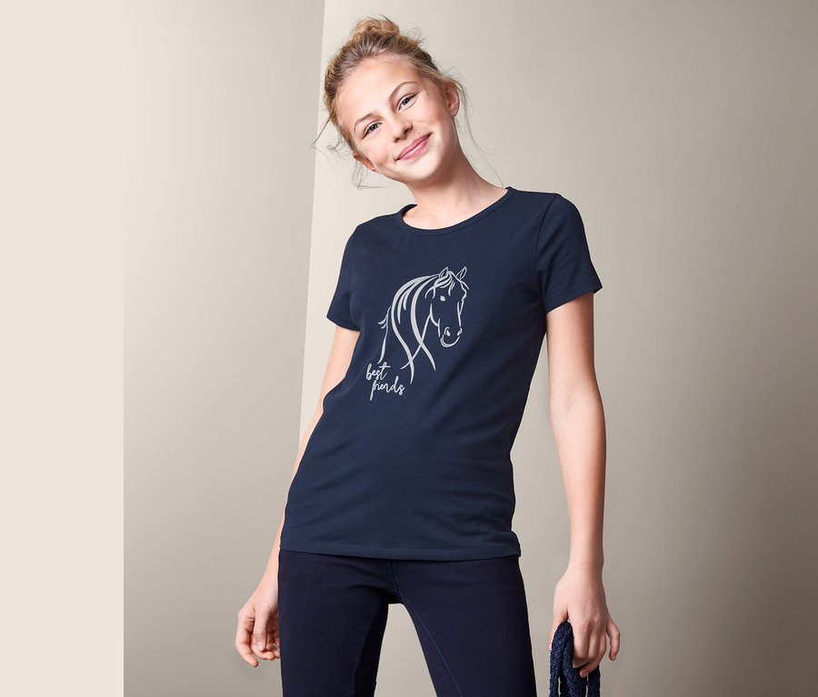Mädchen trägt ein dunkelblaues T-Shirt mit Pferdemotiv und dem Schriftzug "Best Friends" und hält einen blauen Strick in der Hand. Sie trägt Jeans. Im Hintergrund eine beige Wand. 2 T-Shirts.