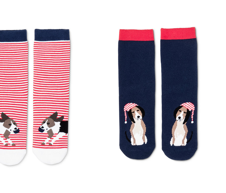 Zwei Paar Antirutsch-Socken. Ein Paar ist rot-weiß gestreift mit einem Hundemotiv. Das andere Paar ist dunkelblau mit rotem Rand und einem Hundemotiv mit Mütze.