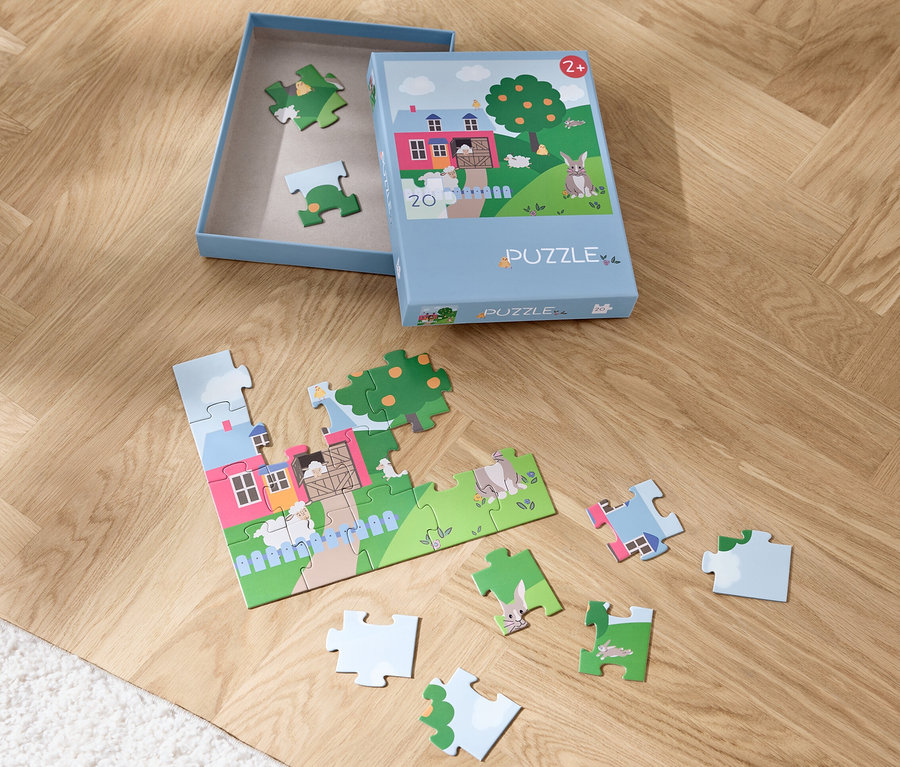 Ein teilweise zusammengesetztes Puzzle »Ostern« und eine Schachtel auf einem Holzboden.