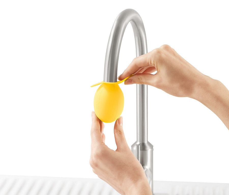 Frau befestigt Wasserhahn-Entkalker-Aufsatz am Wasserhahn eines Spülbeckens.