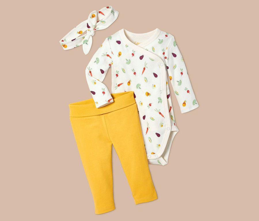 Ein 3-teiliges Baby-Kombi: Gemüse-Body, gelbe Hose und Stirnband.