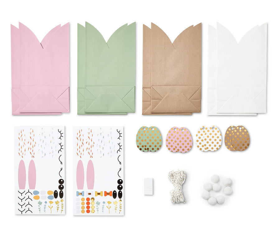 Vier Osterhasen-Geschenktüten in Rosa, Grün, Braun und Weiß sowie Osterdekorationen.