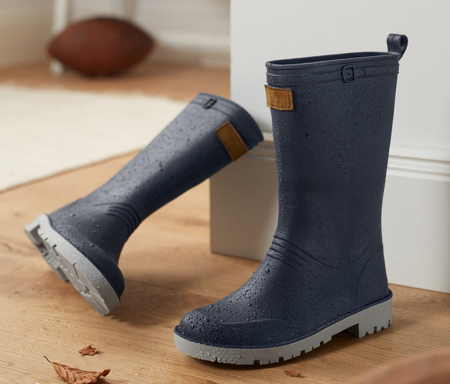 Zwei blaue Gummistiefel stehen auf einem Holzboden.
