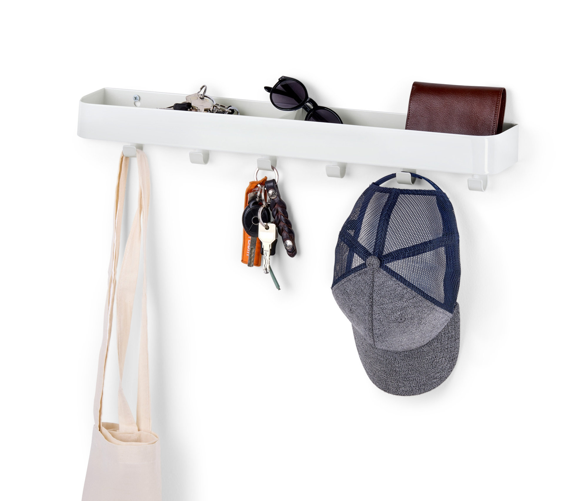 Ein Schlüsselboard mit Ablage an einer weißen Wand mit Schlüsseln, einer Tasche, einer Geldbörse und einer Kappe.