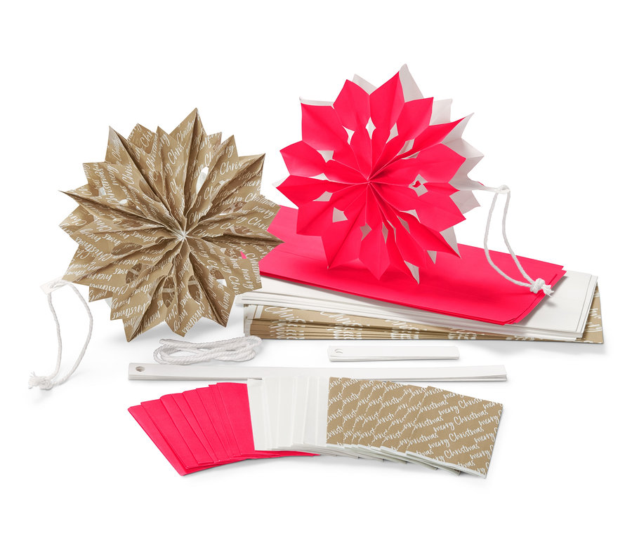 Zwei Papiersterne (einer braun und einer rot) aus dem Papiertüten-Sterne-Bastel-Set liegen aufeinander, zusammen mit einem Stapel Papiertüten, einer Schnur und einem Klebestift.