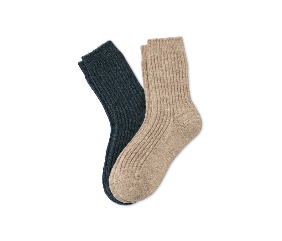 Zwei Paar Ripp-Socken, ein Paar marineblau, ein Paar beige, liegen auf einem weißen Hintergrund.
