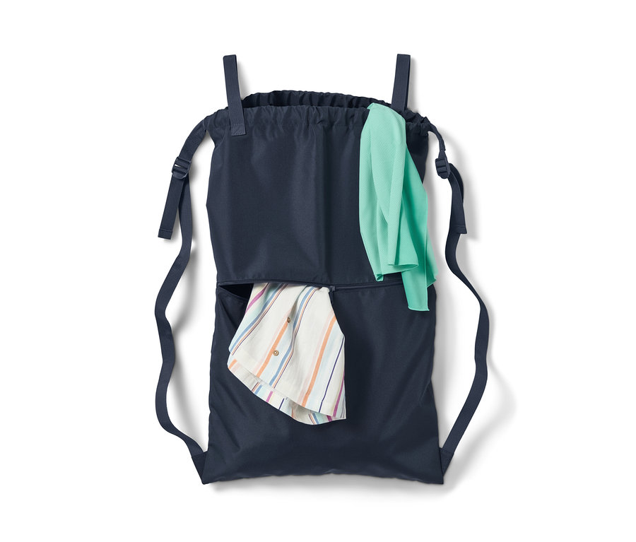 Camping-Wäschesack mit blauen Trägern und zwei Taschen, in einer ein gestreiftes Hemd und in der anderen ein grünes T-Shirt.