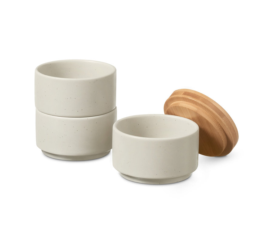 Stapel kleine Gewürzdosen mit Bambusdeckel daneben.