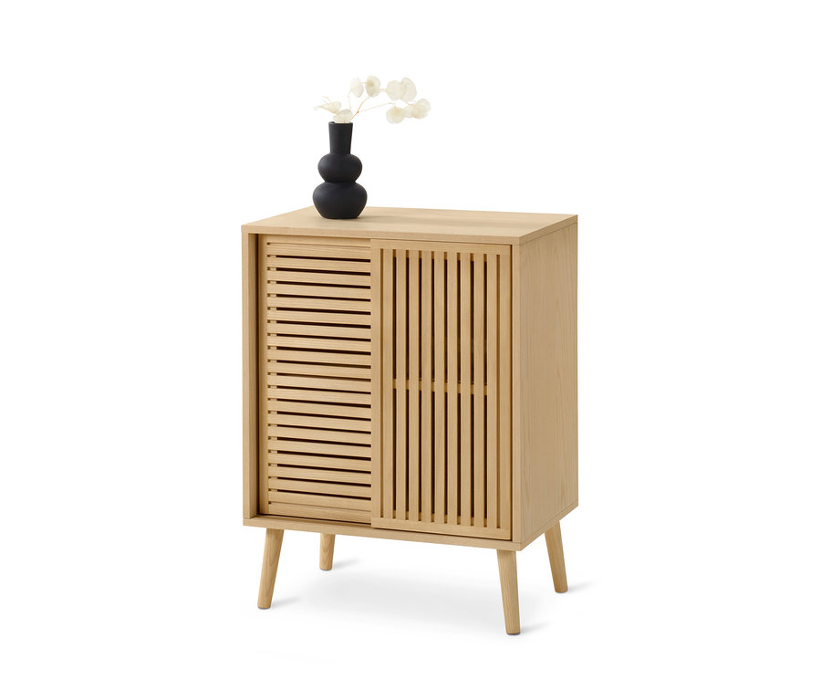 Helle Kommode mit Lamellen-Schiebetüren, darauf eine schwarze Vase mit weißen Blumen.