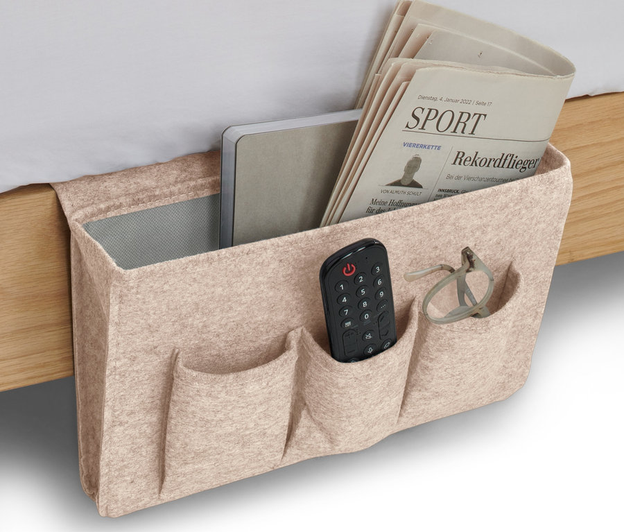 Beiger Bett- und Couchorganizer mit Fernbedienung, Brille, Notizbuch und Zeitung.