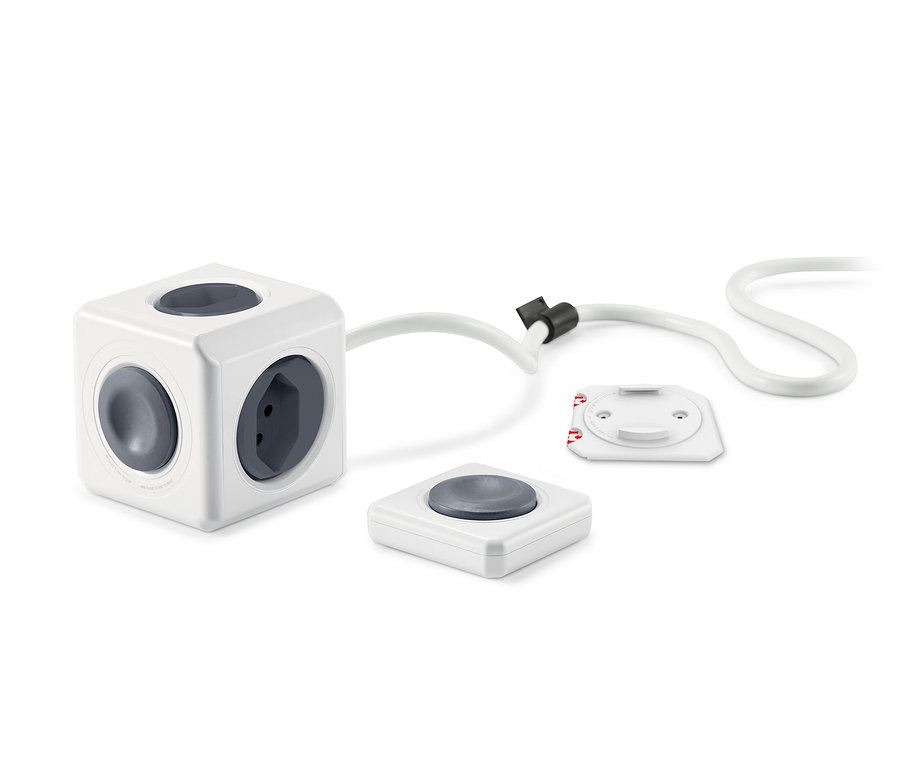 Ein weißer, würfelförmiger Stromadapter mit vier Steckdosen und zwei Fernbedienungen.