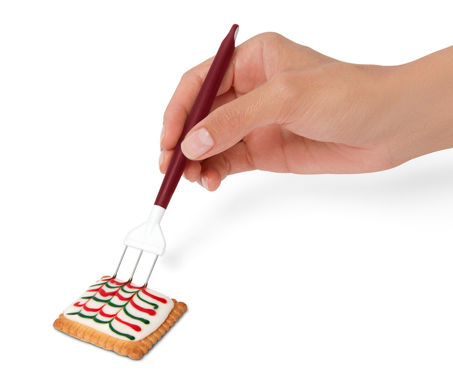Eine Hand verziert einen Keks mit einem Royal-Icing-Set.