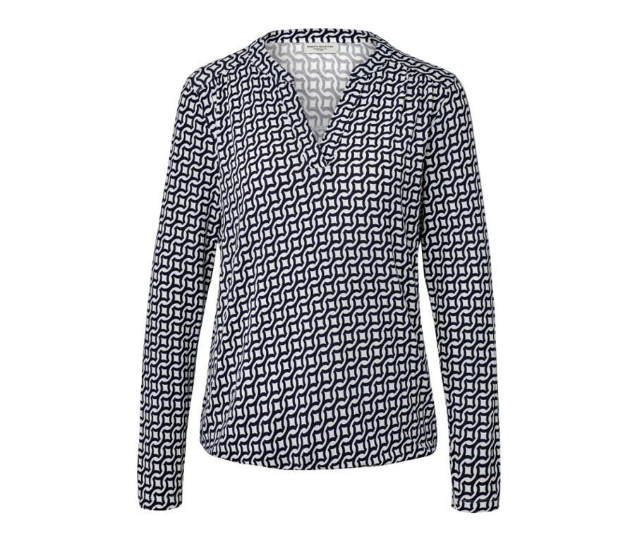Frau sitzt auf einem Stuhl und trägt ein bedrucktes Blusenshirt, navy.