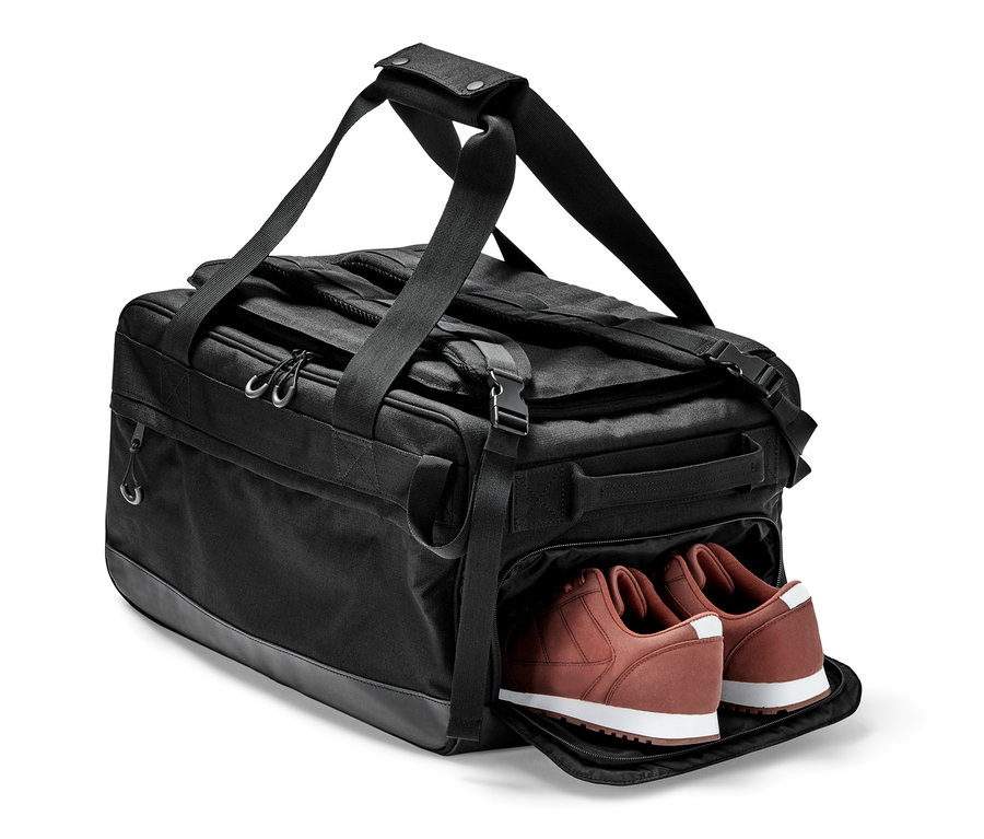Schwarze Duffle-Bag mit einem Paar brauner Schuhe.