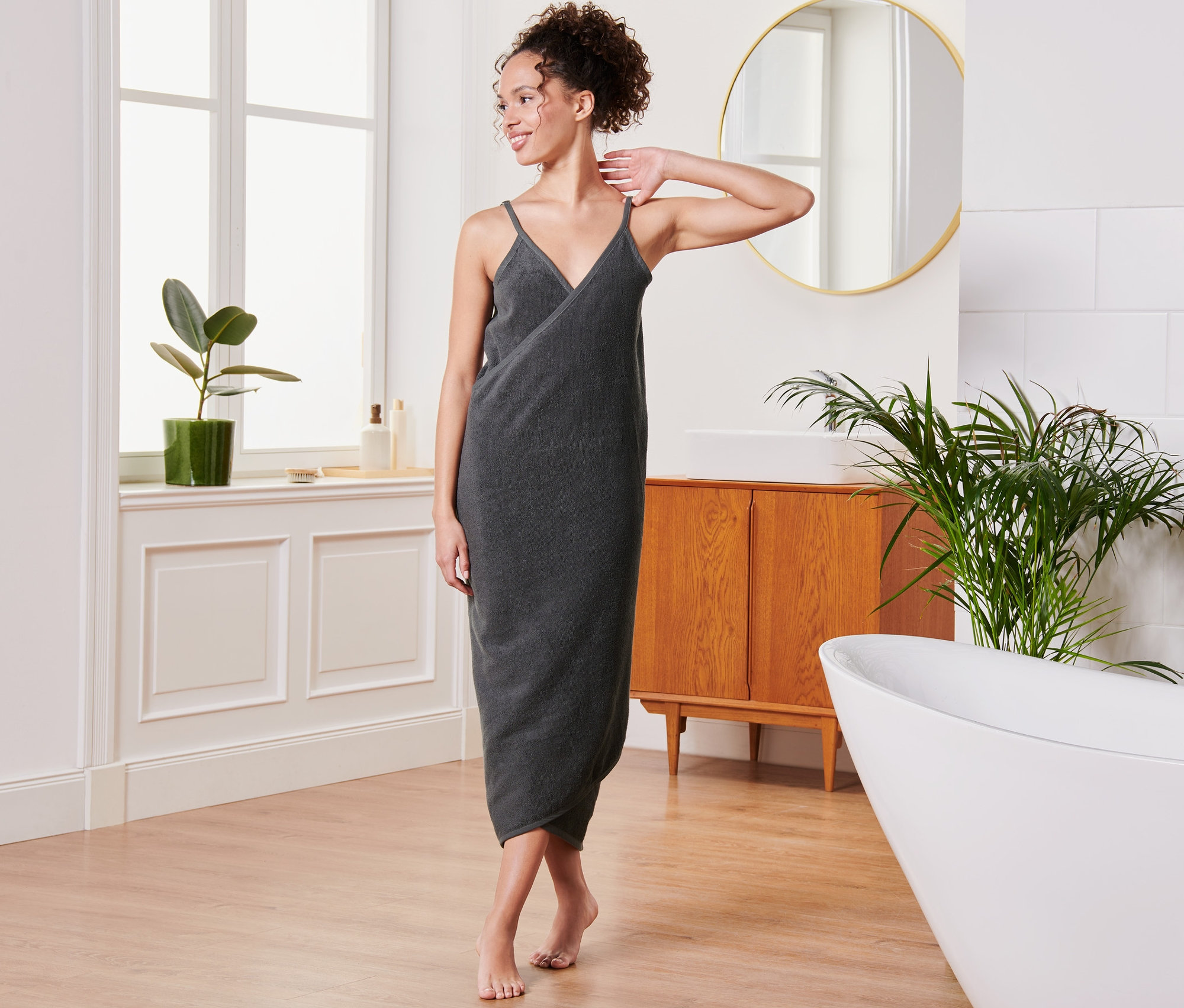 Eine Frau posiert im Badezimmer in einem anthrazitfarbenen Handtuchkleid.