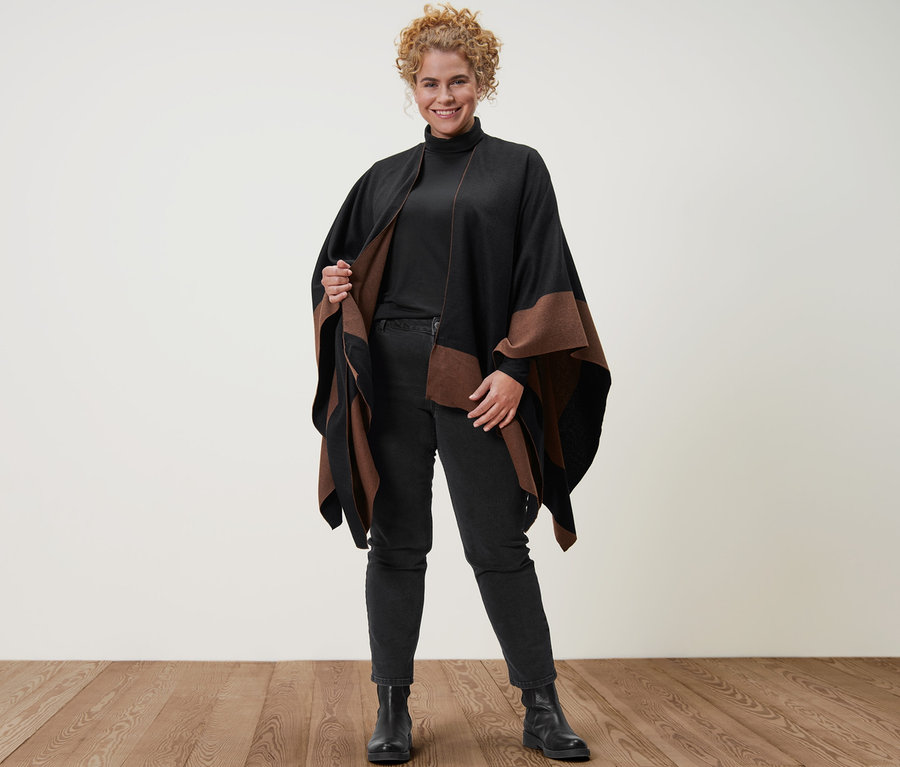 Frau posiert in Wende-Poncho, schwarzem Rollkragenshirt und schwarzen Straight-Denim »Fit Juna«.