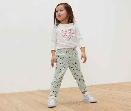 Mädchen steht auf Holzboden und trägt eine Kinder-Pull-on-Pants – Fit »Ella«, Beeren.