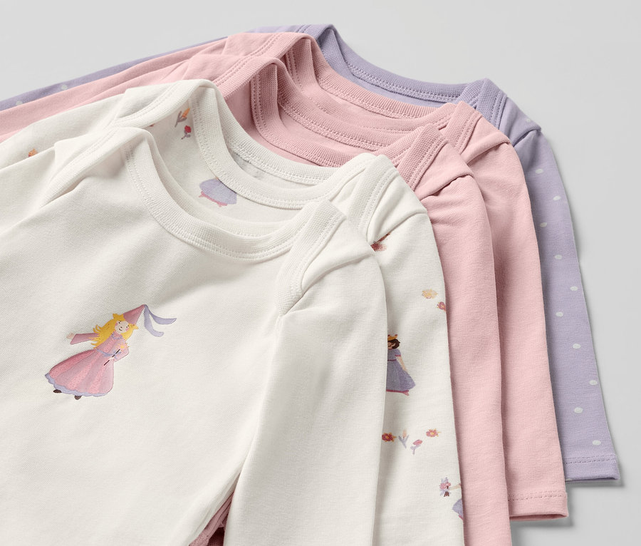 Detailaufnahme von fünf Baby-Bodys mit Mitwachsfunktion und Prinzessinnen-Motiv.