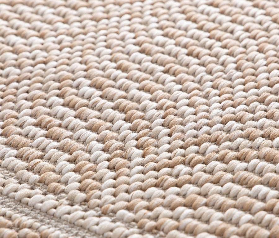 Nahaufnahme eines beigen Teppichs »Twine« mit Fischgrätenmuster.
