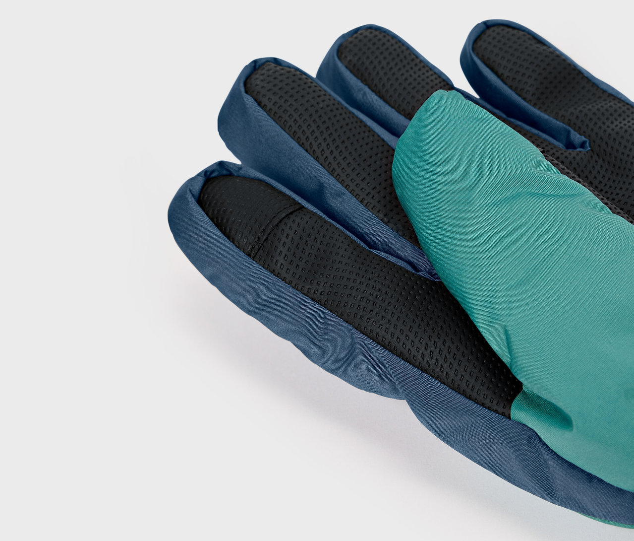 Detailaufnahme eines blauen Handschuhs mit schwarzer Handfläche und grünem Finger.