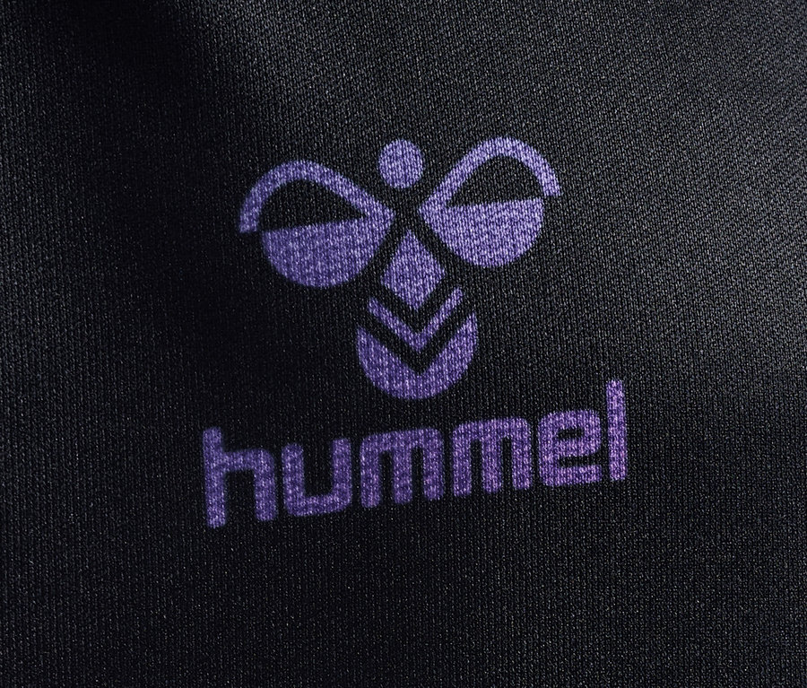 Detailaufnahme des Hummel-Logos und Schriftzugs auf einem schwarzen T-Shirt von HUMMEL HMLJR shimmer T-Shirt S/S.