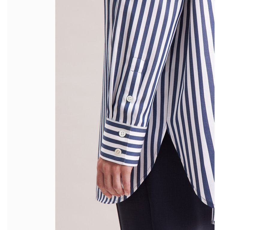 Detailansicht einer Person, die eine gestreifte Seidensticker Oversize Longbluse trägt.